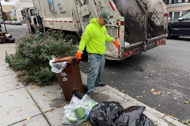 A sanitation worker dragging a bin for composting